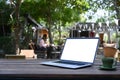 Laptop computer with blank screen and coffee cup on wooden at outdoor cafe. Royalty Free Stock Photo
