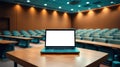 Laptop with blank screen on a table in a lecture hall. Perfect for presentations or online learning