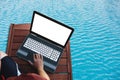 Laptop computer blank white screen, on wooden table on the water in swimming pool Royalty Free Stock Photo