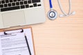 Laptop computer with blue stethoscope on wooden desk. Royalty Free Stock Photo