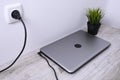 Laptop, computer is charging from a 220-volt outlet on a desk near the wall. Energy, accumulation. Mockup Royalty Free Stock Photo