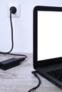 Laptop, computer is charging from a 220-volt outlet on a desk near the wall. Energy, accumulation. Mockup Royalty Free Stock Photo