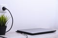 Laptop, computer is charging from a 220-volt outlet on a desk near the wall. Energy, accumulation. Mockup Royalty Free Stock Photo