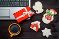 Laptop computer, Christmas present, cup of coffee and  gingerbread cookies on dark wood background, copy space. Top view. Royalty Free Stock Photo