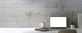 Laptop computer, coffee cup, books and houseplant on white table against brick wall. Blank screen, copy space for your advertise Royalty Free Stock Photo