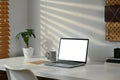 Laptop computer, coffee cup, books and potted plant on white table. Blank screen for text information or content Royalty Free Stock Photo