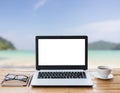 Laptop computer and coffee on wood workspace and the beach Royalty Free Stock Photo