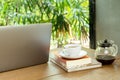 Laptop computer and cup of coffee with book on wooden table in cafe. Royalty Free Stock Photo