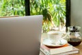 Laptop computer and cup of coffee with book on wooden table in cafe. Royalty Free Stock Photo