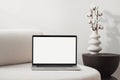 Laptop computer with empty blank mockup screen over white modern living room design. Royalty Free Stock Photo