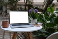 Laptop with empty screen and coffee cup on round table at outdoor cafe. Royalty Free Stock Photo