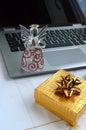 Laptop computer with a glass angel and a yellow golden gift box Royalty Free Stock Photo