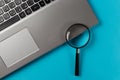 Laptop computer with magnifying glass on blue background, concept of search Royalty Free Stock Photo