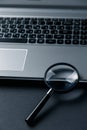 Laptop computer with magnifying glass on dark background, concept of search Royalty Free Stock Photo