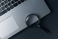 Laptop computer with magnifying glass on dark background, concept of search Royalty Free Stock Photo