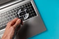 Laptop computer and man`s hand with magnifying glass on blue background, concept of search Royalty Free Stock Photo