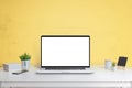 Laptop computer mockup on office desk with yellow wall in background Royalty Free Stock Photo