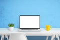 Laptop computer mockup on white wooden desk. Creative scene with plant and yellow coffee mug and blue wall in background Royalty Free Stock Photo