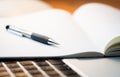 Laptop Computer on a Modern Wooden Business Desk with a Notepad and Pen in Unfocused Background