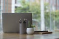 Laptop computer, pencil holder, potted plant and books on wooden office desk Royalty Free Stock Photo