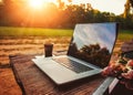 Laptop computer on rough wooden table with coffee cup and bouquet of peonies flowers in outdoor park Royalty Free Stock Photo