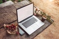 Laptop computer on rough wooden table with coffee cup and bouquet of peonies flowers in outdoor park. Royalty Free Stock Photo