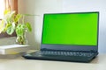 Laptop computer showing chroma green screen on LCD display stands on a desk with books next to ready for further design and copy Royalty Free Stock Photo