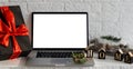 Laptop computer with white blank empty mock up screen on Merry Christmas table with presents gifts boxes in warehouse