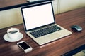 Laptop computer and white blank screen on wood table in office.