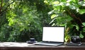 Laptop computer with white blank screen on wooden table in the garden Royalty Free Stock Photo