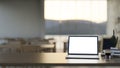 A laptop computer white-screen mockup on a wooden desk in a comfortable and contemporary restaurant Royalty Free Stock Photo