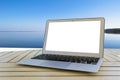 Laptop computer on wooden table. Top ocean view. Tropical island background. Open blank laptop computer empty space. Front view