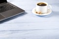 Laptop with cup of coffee on light blue old wooden table. Notebook with cup of fresh coffee in home office. Working from home Royalty Free Stock Photo