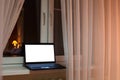 Laptop with cutout screen of monitor laying on windowsill at evening time in room