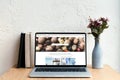 laptop with depositphotos website on screen books and flowers in vase