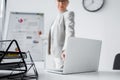 laptop on desk near blurred businesswoman