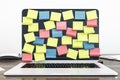 Laptop display with empty colored sticker notes on brown office table