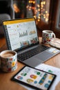 Laptop displaying analytics dashboard with coffee cups on a cozy wooden table Royalty Free Stock Photo