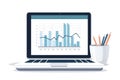 A laptop displaying bar and line charts next to a pencil holder, representing data analysis, business performance tracking,