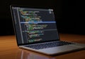 A laptop displaying colorful lines of code on a dark theme interface Royalty Free Stock Photo