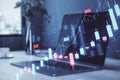 A laptop displaying stock market chart graphics with a holographic overlay concept on a modern office desk Royalty Free Stock Photo