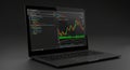 A laptop displays a dual-screen setup with coding on the left and a stock market chart Royalty Free Stock Photo