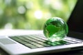 laptop with earth globe on wooden table and green bokeh background Royalty Free Stock Photo