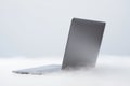 Laptop emerging from white smoke on a clean background symbolizing cloud computing technology and digital transformation Royalty Free Stock Photo