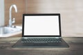 Laptop with empty blank screen on wooden tabletop with modern blur kitchen background