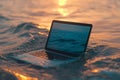 A laptop floats on calm, golden sea at sunset, creating a thought-provoking blend of technology and nature