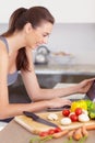 Laptop, food and a woman reading a recipe in her kitchen with vegetarian ingredients for health. Computer, smile and a