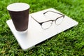 Laptop on the green grass. coffee and glasses. Office and working space in nature