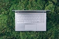 Laptop on green grass, moss background. Ecology travel, work outside office concept. Mindfulness, biophilic design