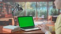 A laptop with a green screen chroma key on the library table. Advertising area, workspace mock up. Royalty Free Stock Photo